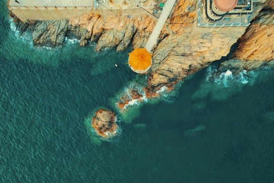 岩石海岸的空中视角 有一座灯塔屹立在悬崖上 俯瞰着海洋和岩石。