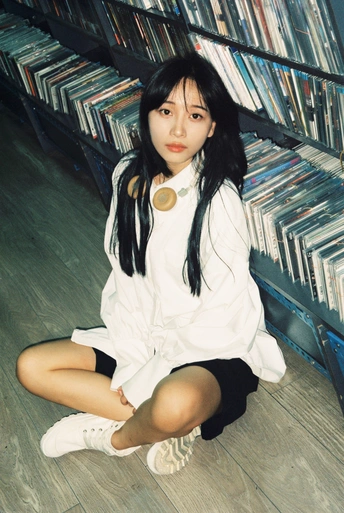 一个年轻女孩坐在图书馆的地板上 图书馆里摆满了cd和dvd