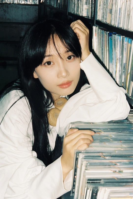 图书馆里 一位年轻女子在装满cd的书架前摆姿势