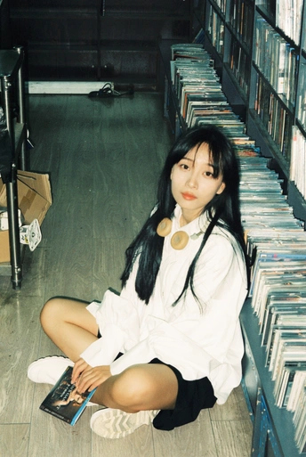 一个年轻女孩坐在图书馆的地板上 旁边放着CD