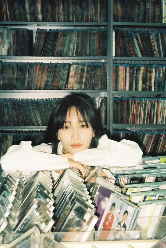 一个年轻女孩躺在装满cd的架子前