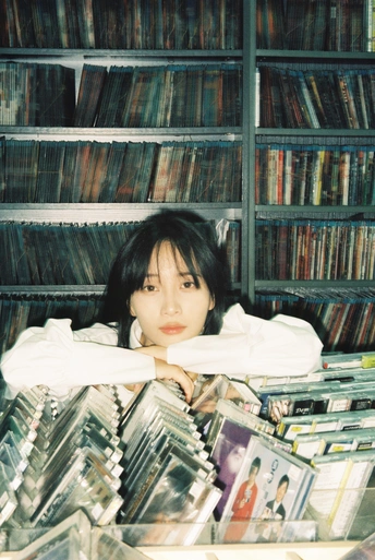 一个年轻女孩躺在装满cd的架子前