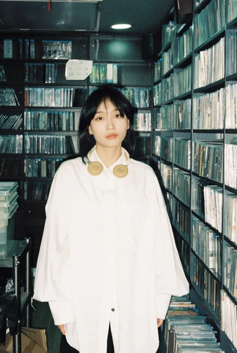 一个穿着白衬衫的年轻女子站在一个摆满书架的图书馆里