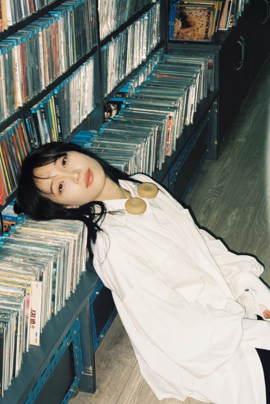 一个年轻的女人躺在图书馆里 许多书架上都是书和光盘