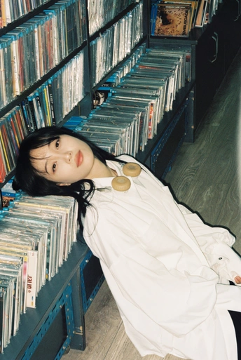 一个年轻的女人躺在图书馆里 许多书架上都是书和光盘