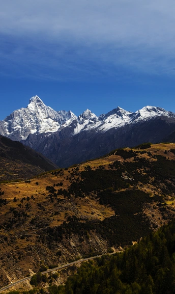 a road winding through a valley below a mountain r