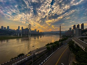 夕阳下的城市 桥跨河流 背景是高速公路和天际线 太阳低垂在天空中。