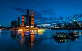 夜晚照亮了一大片水域 水中停着船 背景是城市天际线。