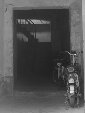 一张黑白照片 展示了一个车库 里面停着一辆摩托车和一辆自行车。
