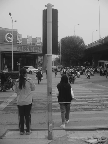 一张黑白照片 描绘了人们在路口过马路 摩托车在街道上行驶。