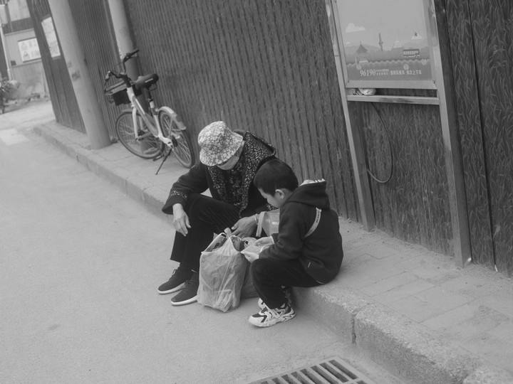 一张老照片 一对男女坐在街边的路缘上。