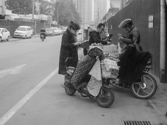 一张黑白照片 一个男子骑着滑板车在街上