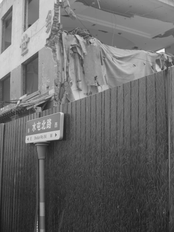 一块黑白相间的街道标志悬挂在一栋建筑旁边的一堵墙上