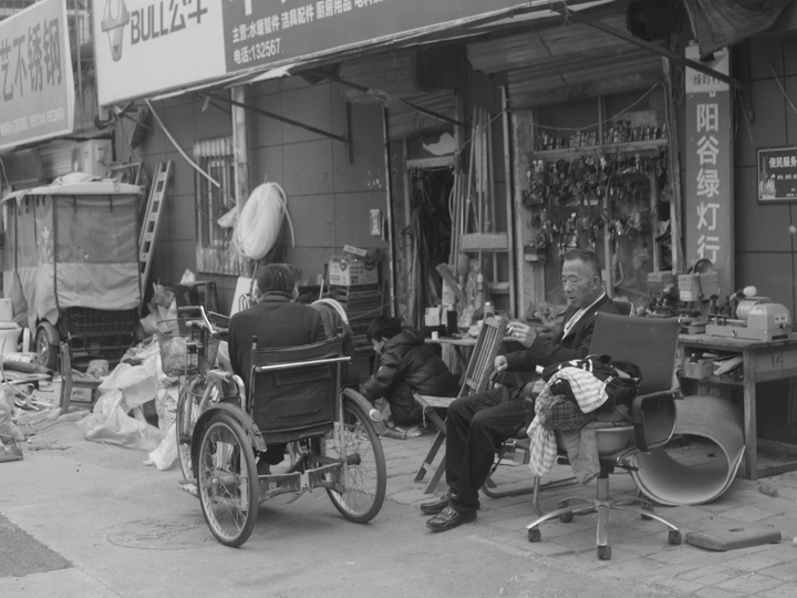 一张老黑白照片 一个坐在轮椅上的男人坐在商店前。