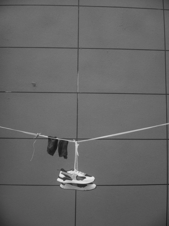 挂在绳子上的鞋子 对着黑白墙 