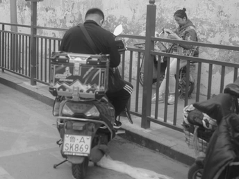 一个男子骑着滑板车沿着人行道行驶 旁边的人们坐在自行车上。