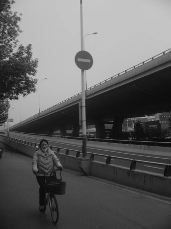 一位妇女骑自行车沿着桥下的一条街道