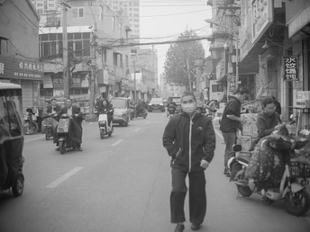 一张亚洲城市的黑白照片 有人们在行走和摩托车。