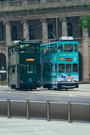 一辆蓝色双层公交车在靠近建筑物的街道上行驶
