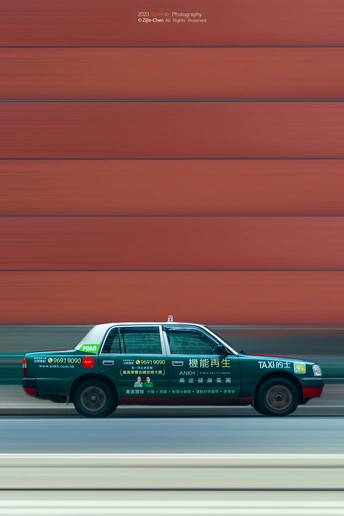 在一辆行驶在高速公路前的墙上贴着广告的出租车