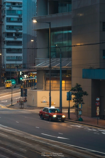 夜晚的城市街道 高楼林立 一辆红车在交通灯下驶过。