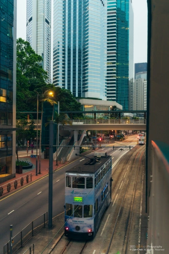 一辆蓝色和白色的公交车在大城市的街道上行驶 街道两旁有高大的建筑。