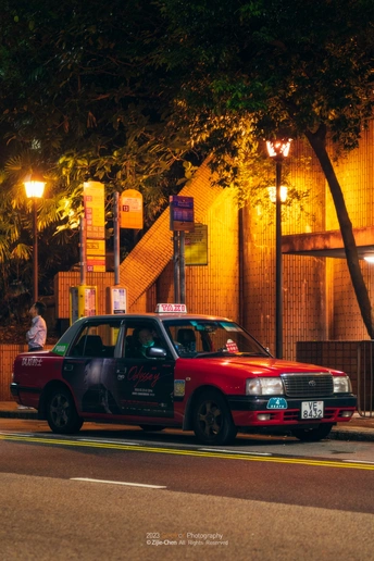 一辆红色的车在夜晚驶过一栋楼旁的街道