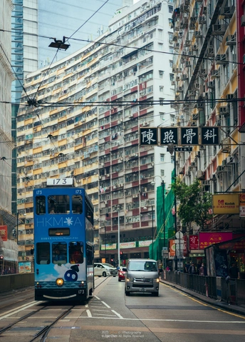 蓝色公交车行驶在旁边有高楼大厦的街道上