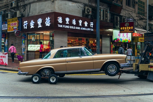 路边停着一辆旧车 一辆拖车正在街道上行驶。