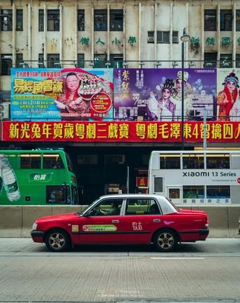 一辆红色的汽车在有大型广告牌和路边的标志的街道上行驶