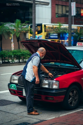 一个老人在看着一辆打开引擎盖的红色汽车