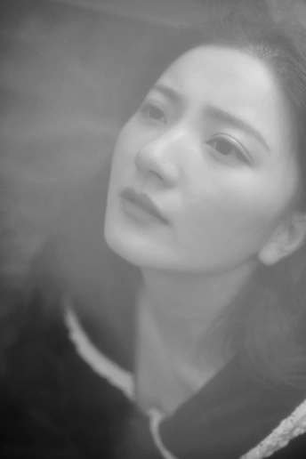 一张黑白照片 一位年轻女子正在通过窗户