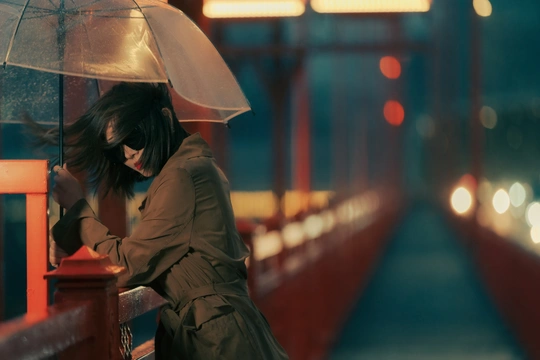 一位女性在夜晚穿过一座桥 手里拿着一把伞。