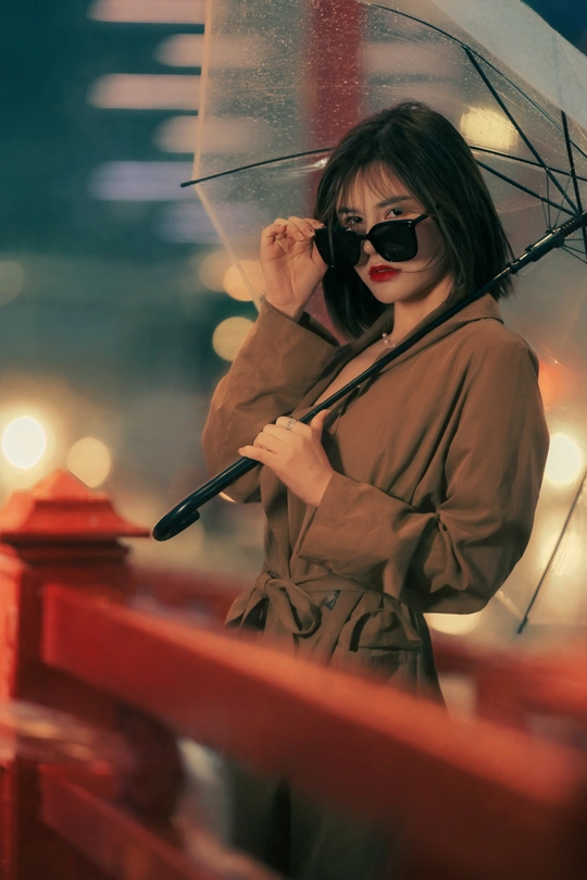 一个戴太阳镜的年轻女子在雨中拿着雨伞