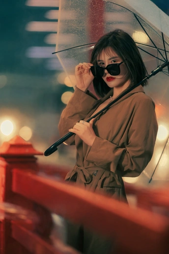 一个戴太阳镜的年轻女子在雨中拿着雨伞