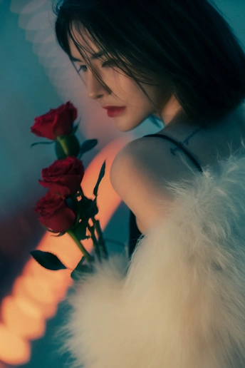 一位穿着白色连衣裙的年轻女子手拿红玫瑰