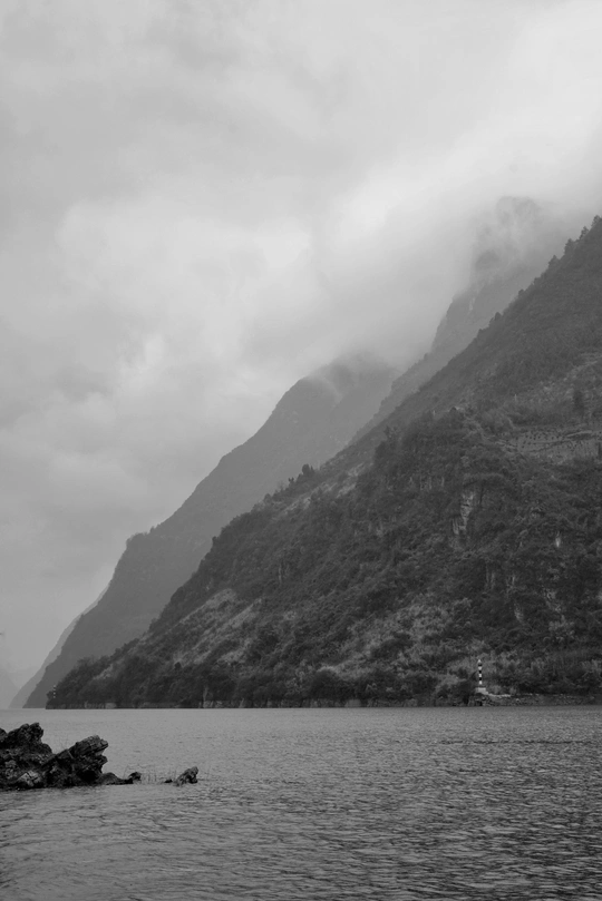 一艘船在有山丘背景的水域上 有雾和云。