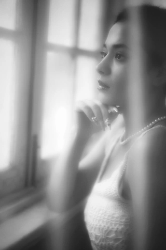 一张黑白照片 一位年轻女子穿着白色裙子 正看着镜子里的自己的倒影。