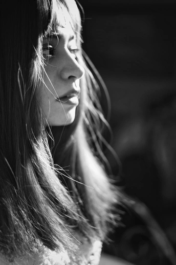 一张黑白照片 一位年轻女子正在窗口向外看。