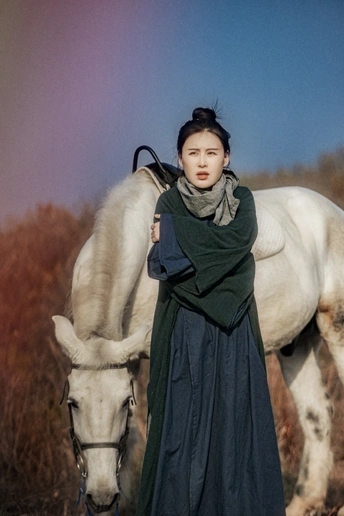 一个穿着连衣裙的年轻女子站在一匹白马旁边