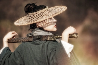 一位穿着黑色衣服的女士拿着一根棍子和一顶帽子