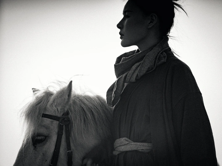 一张黑白照片 一位年轻女子骑着一匹白马。