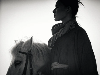 一张黑白照片 一位年轻女子骑着一匹白马。