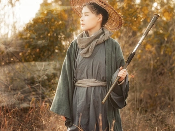 一位穿着costume（服装）的年轻女子 戴着帽子 拿着权杖。