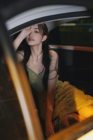 一个穿着黄色连衣裙的年轻女子坐在车里看着窗外