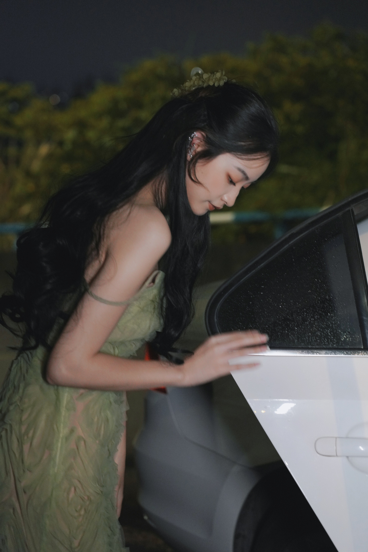 一位穿着连衣裙的年轻女士站在一辆开着门的白色汽车旁边