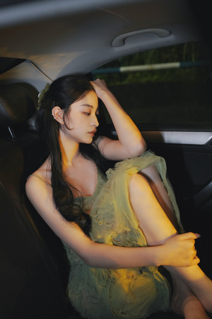 穿着绿色连衣裙的年轻女子晚上坐在车里