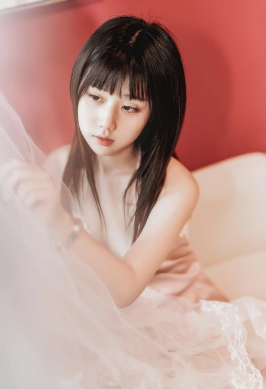 一个穿着白色连衣裙的年轻女子坐在红色沙发上