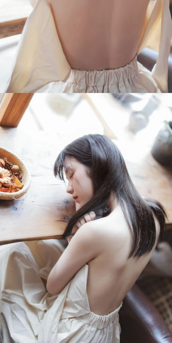 一个穿着连衣裙的年轻女子坐在桌子上 桌子上放着食物。