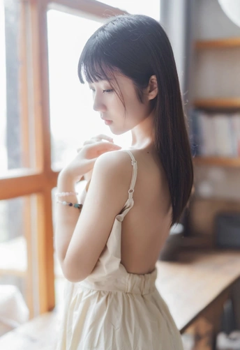 一位穿着白色连衣裙的年轻女子正在窗户旁向外看